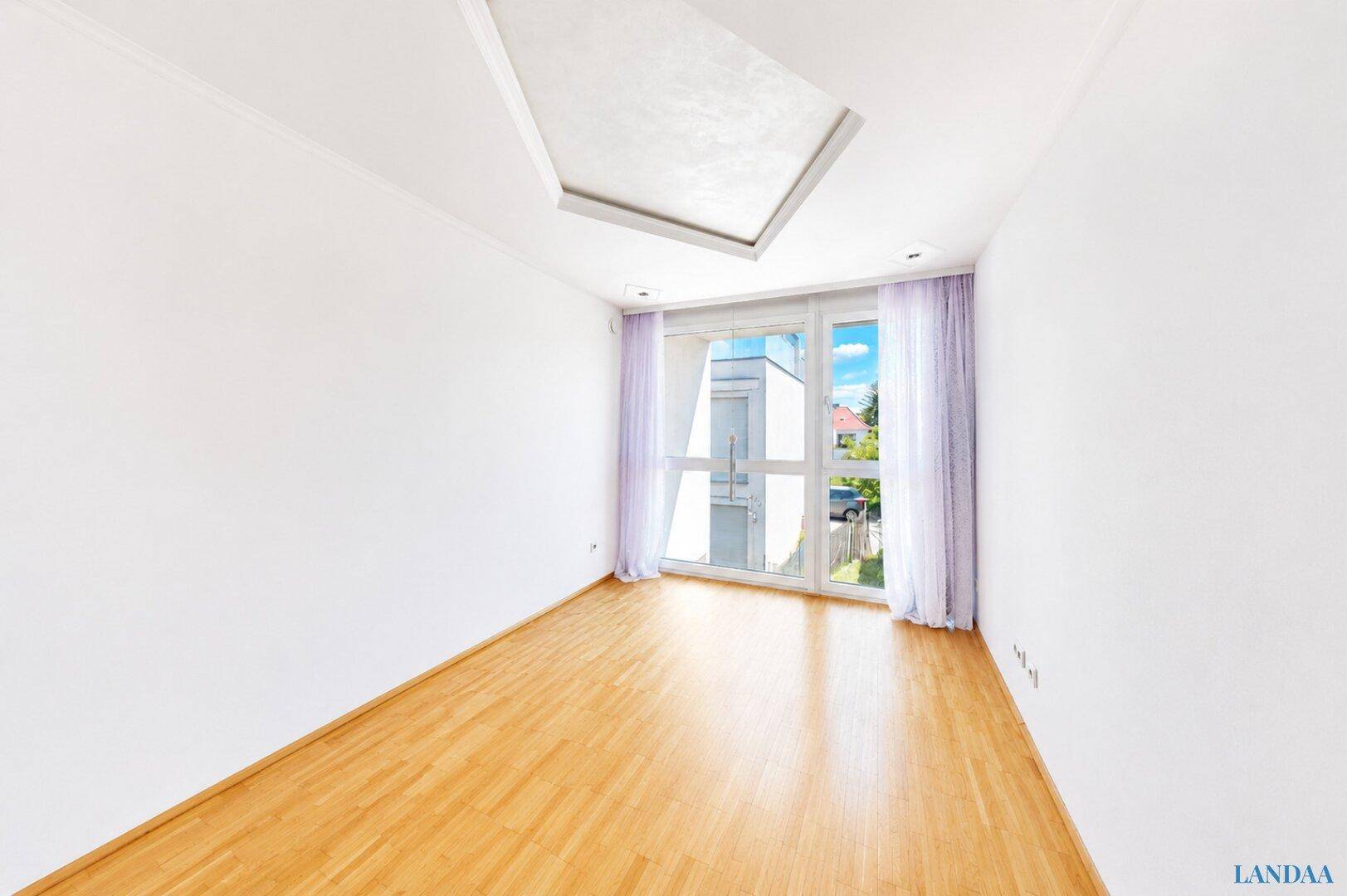 Leeres Zimmer mit hellem Holzboden und großem Fenster für viel Tageslicht.