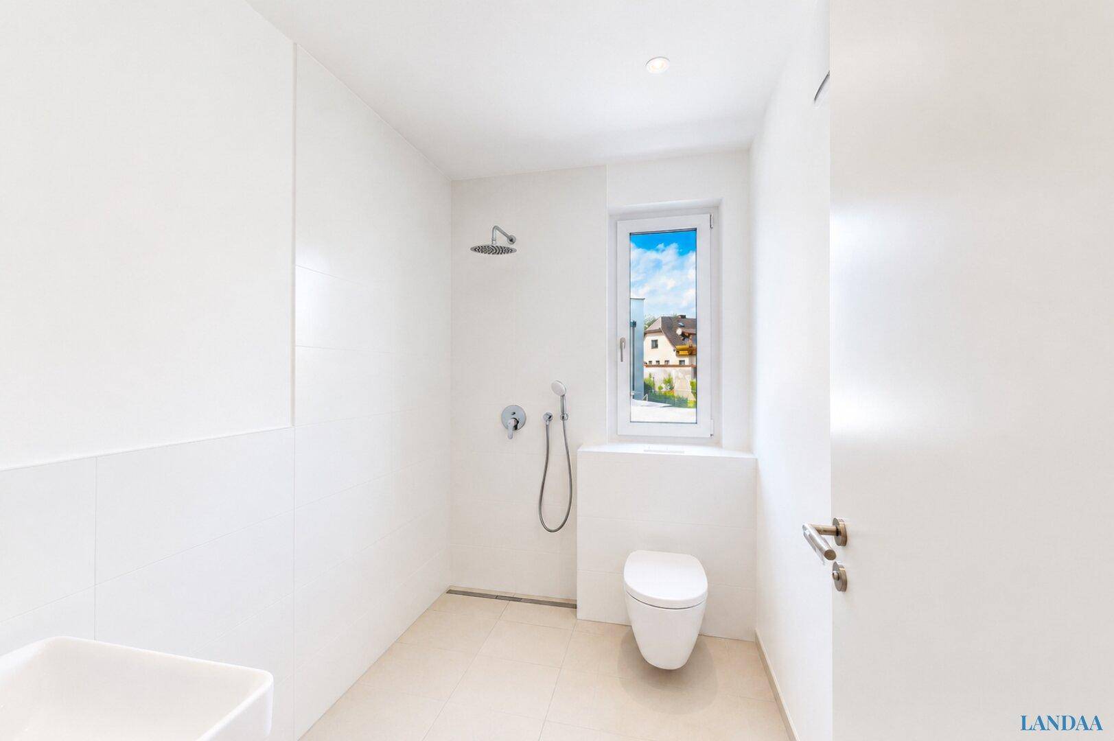 Modernes Badezimmer mit ebenerdiger Dusche, wandhängendem WC und Fenster für Tageslicht.