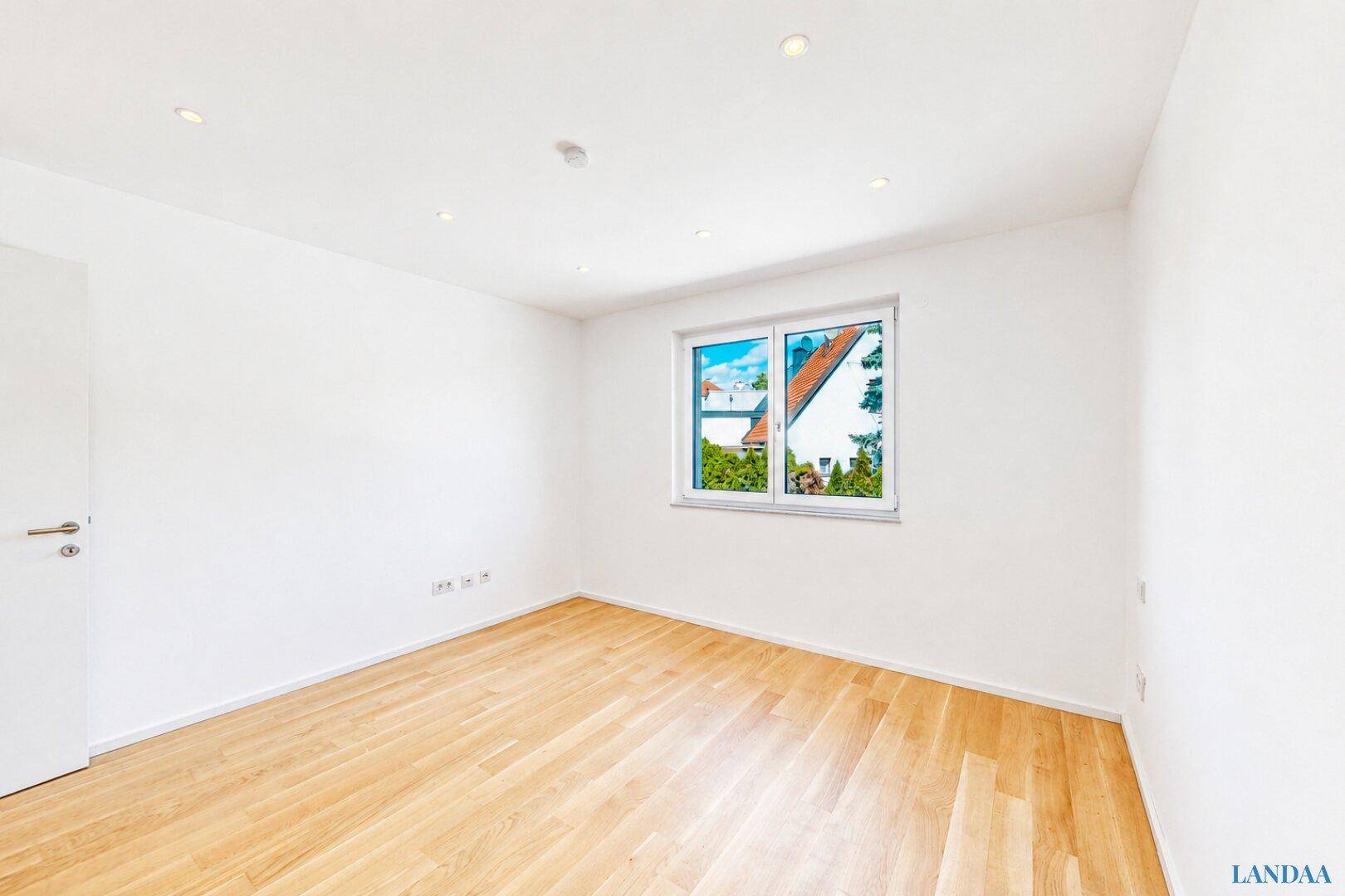 Leerer, heller Raum mit Holzboden und Fenster, ideal für individuelle Gestaltung.