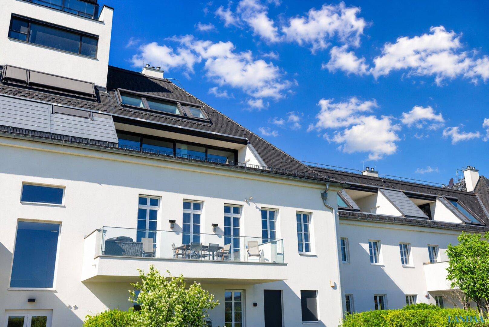 Seitenansicht des modernen Gebäudes mit Balkonen, großen Fenstern und Dachgauben.