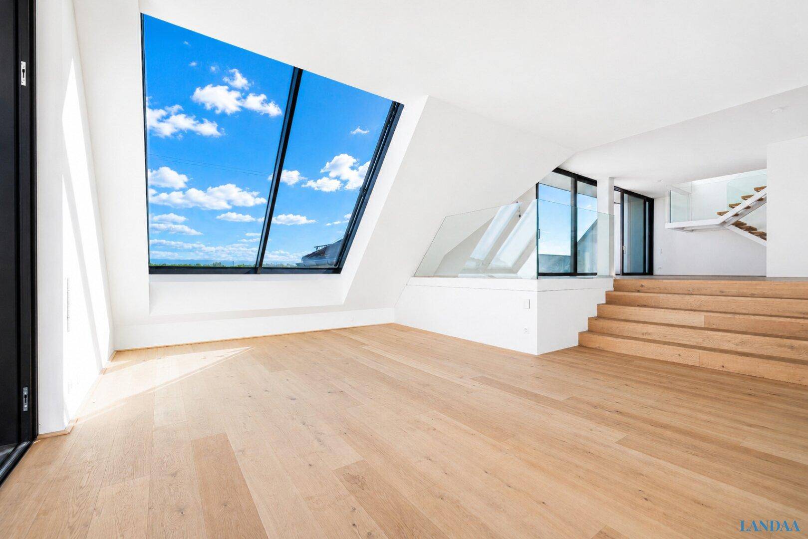 Offener, heller Wohnbereich mit Holzboden, moderner Treppe und großen Fenstern mit Seeblick.