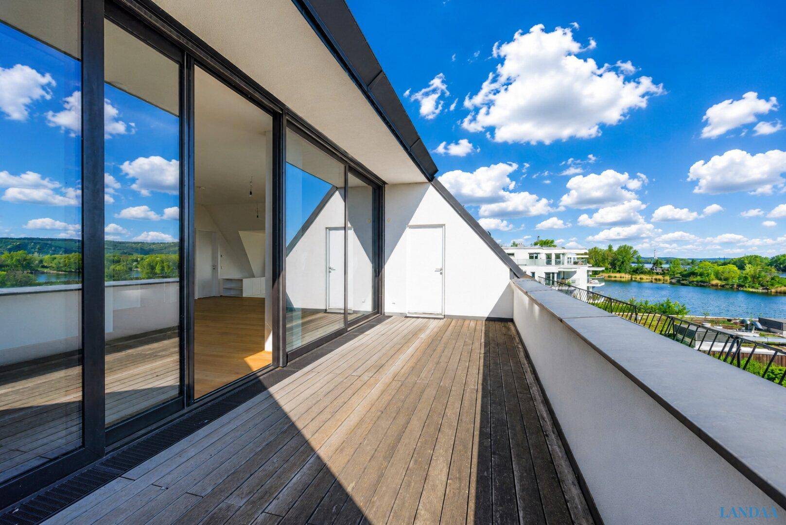 Geräumige Holzterrasse mit Blick auf den See und die umliegende Natur, ideal zum Entspannen.
