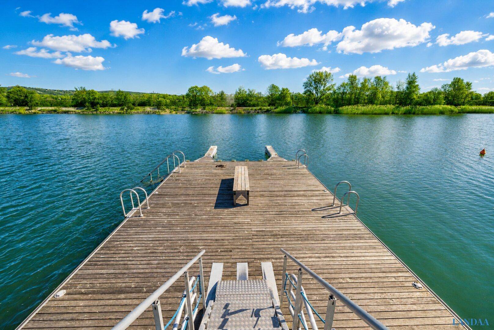 Holzsteg am Seeufer mit Badeleiter und Sitzbank, ideal für Wassersport und Entspannung.