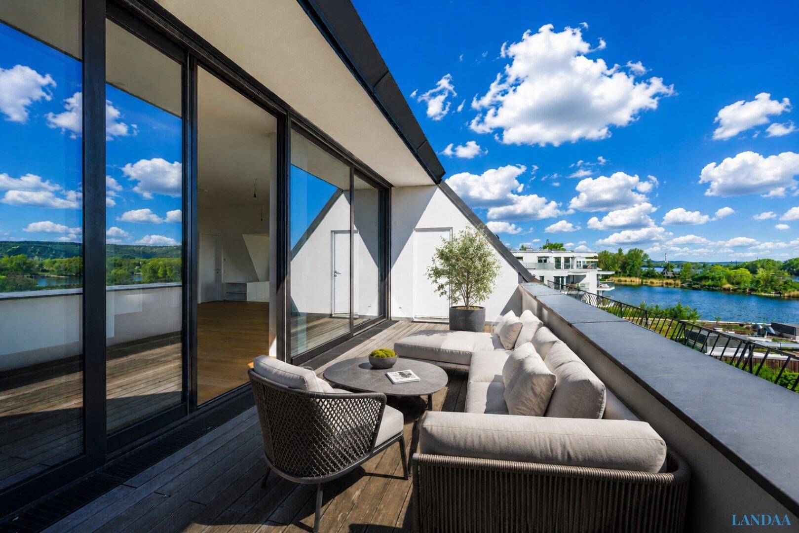 Möblierte Dachterrasse mit bequemen Sitzgelegenheiten und weitem Blick über den See und die umliegende Landschaft.