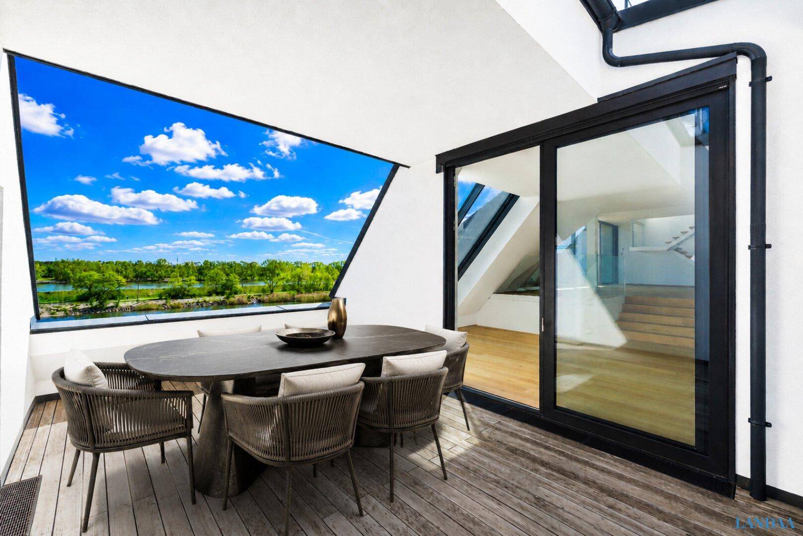Gemütliche Terrasse mit Esstisch und Stühlen, ideal für Mahlzeiten im Freien mit Panoramablick auf den See.
