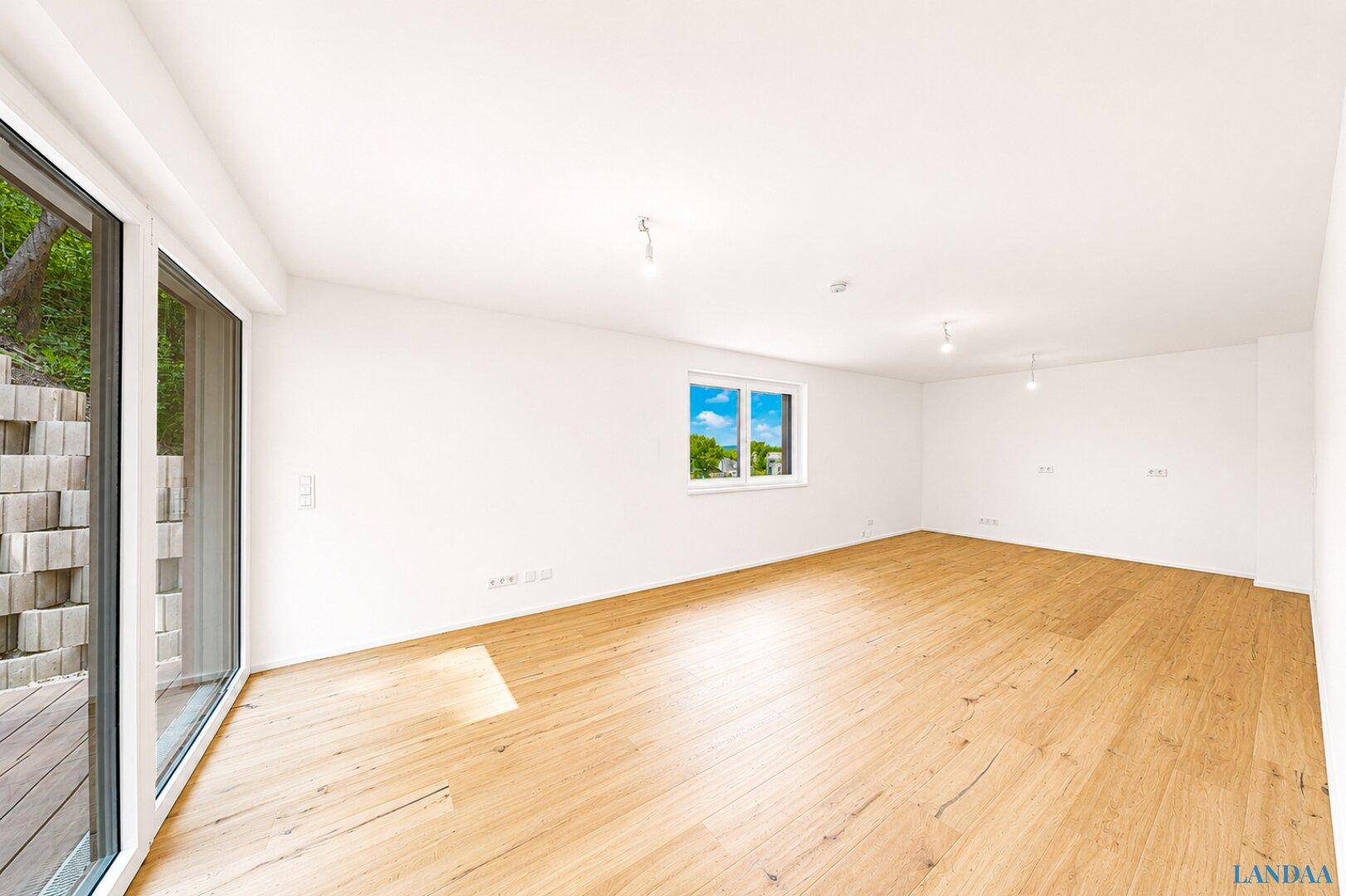 Lichtdurchfluteter Raum mit Holzboden und Zugang zu einer Terrasse, ideal für verschiedene Nutzungen.