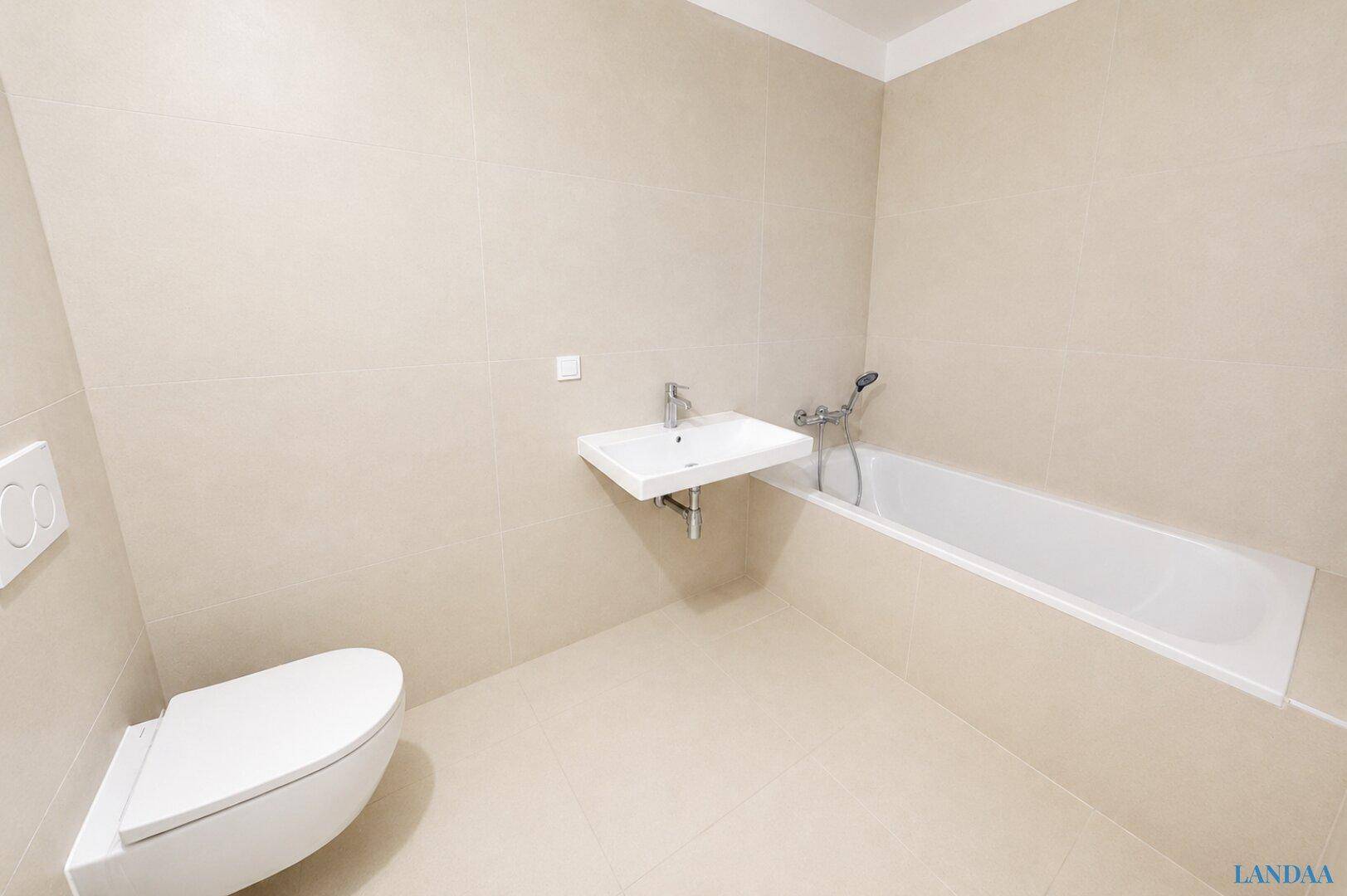 Modernes Badezimmer mit beigen Fliesen, wandhängendem WC, Waschbecken und Badewanne.