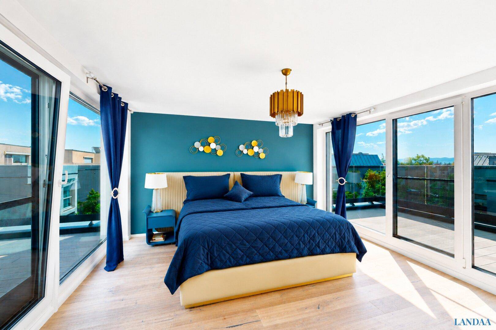 Modernes Schlafzimmer mit blauer Akzentwand, großen Fenstern und direktem Terrassenzugang.