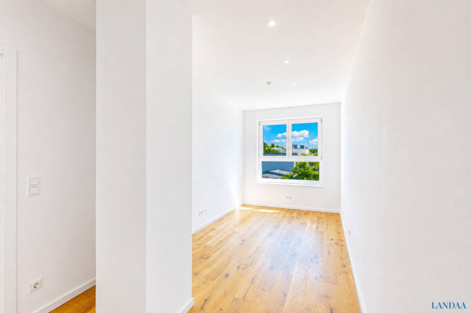 Helles Zimmer mit Holzboden und großem Fenster, ideal als Schlaf- oder Arbeitszimmer.