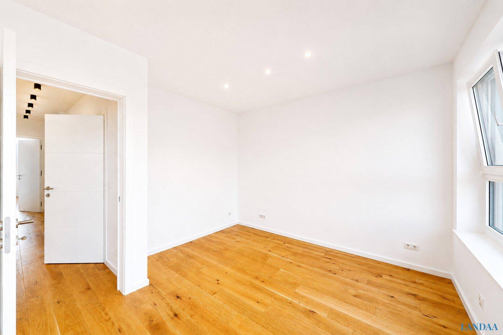 Geräumiges Zimmer mit Holzboden und weiß gestrichenen Wänden, bereit zur Einrichtung.