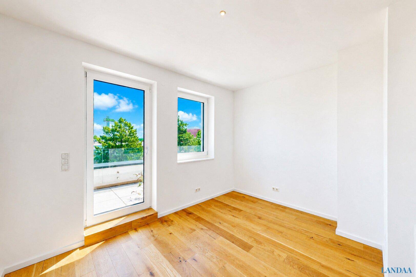 Helles Zimmer mit Holzboden und Zugang zu einem Balkon oder einer Terrasse.