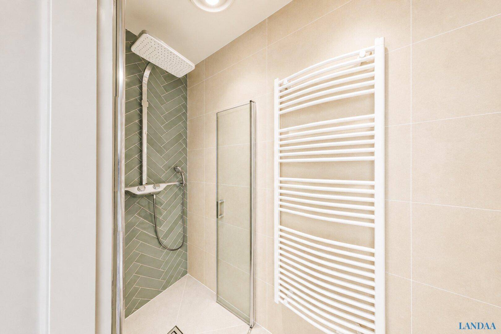 Moderne Dusche mit Regenduschkopf, Glasabtrennung und Handtuchheizkörper.