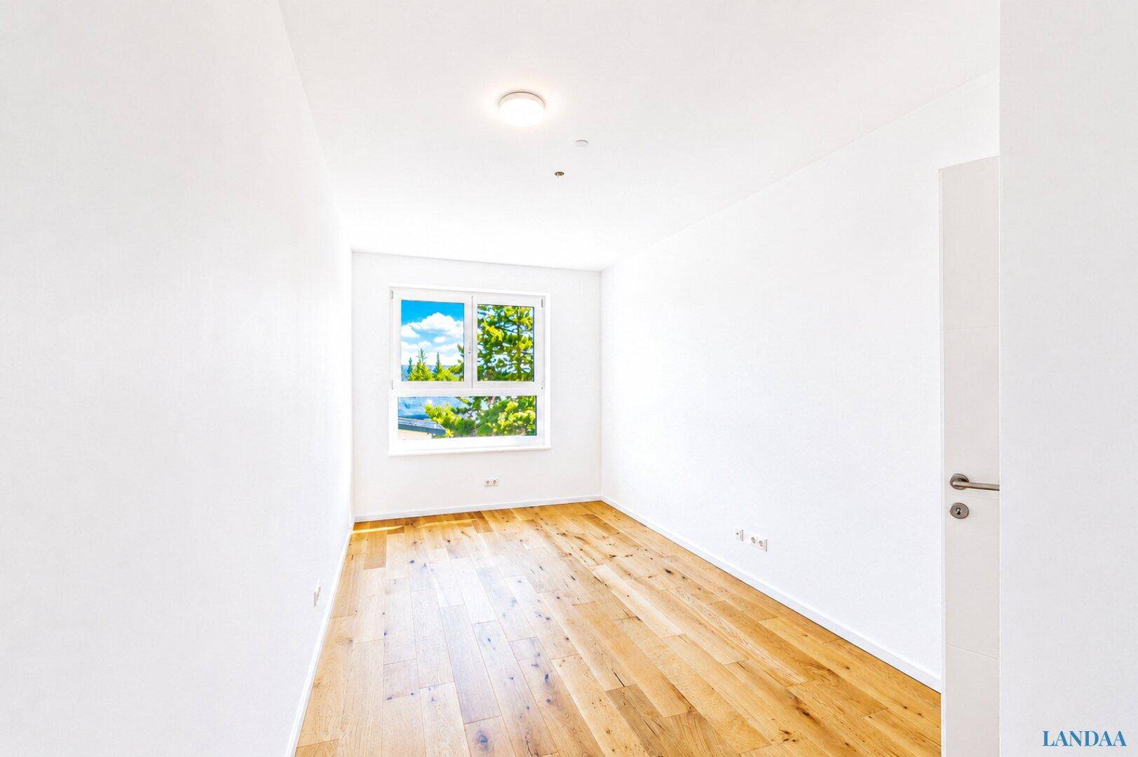 Helles Zimmer mit Holzboden und einem großen Fenster, ideal für ein Kinderzimmer.