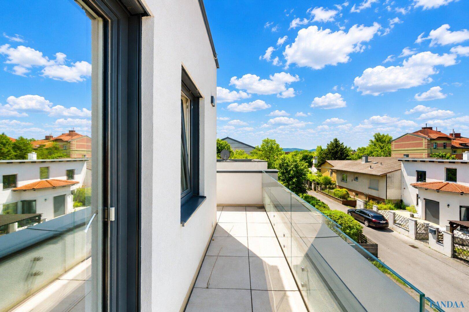 Dachterrasse mit Fliesenboden, Glasgeländer und weitem Blick über die Nachbarschaft.