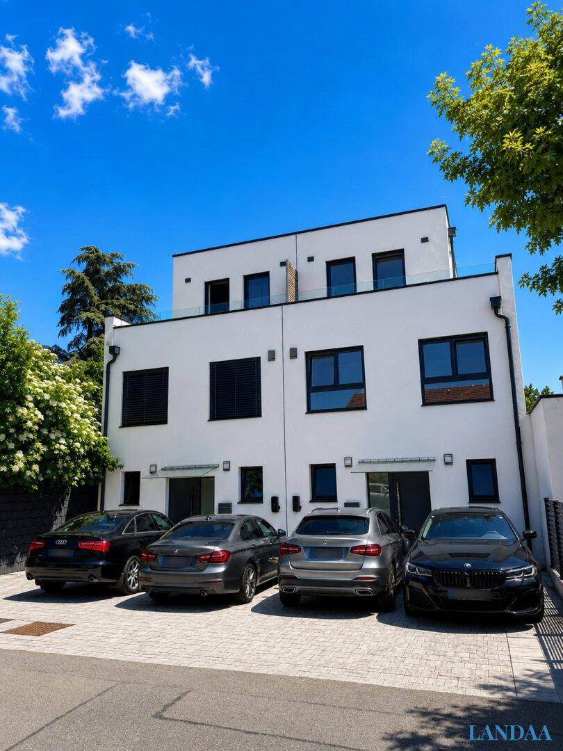 Zeitgenössische Doppelhaushälfte mit geparkten Autos vor der modernen weißen Fassade.