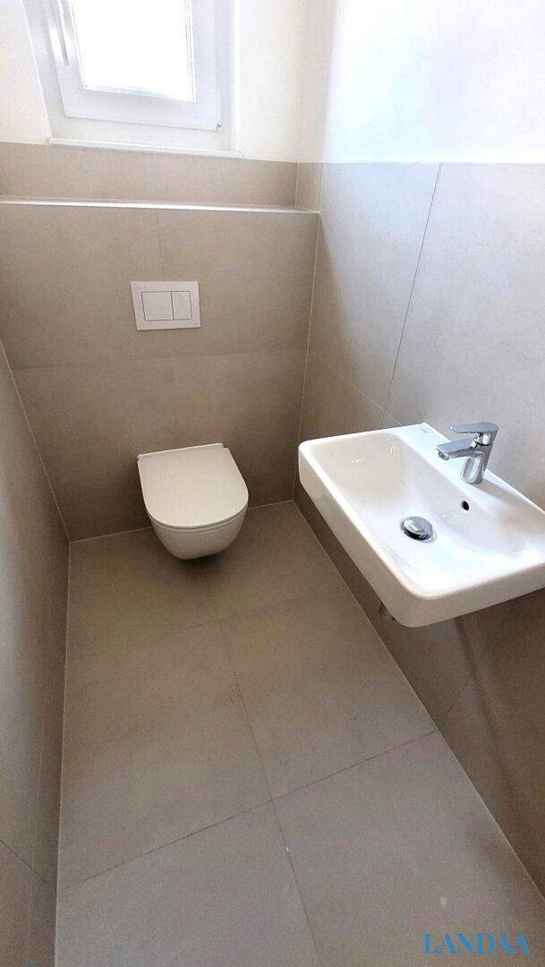 Modernes Gäste-WC mit wandhängender Toilette, kleinem Waschbecken und Fenster.