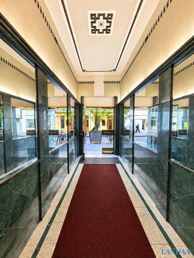 Eleganter Eingangsbereich mit grünem Marmor, Spiegeln und einem roten Teppich.