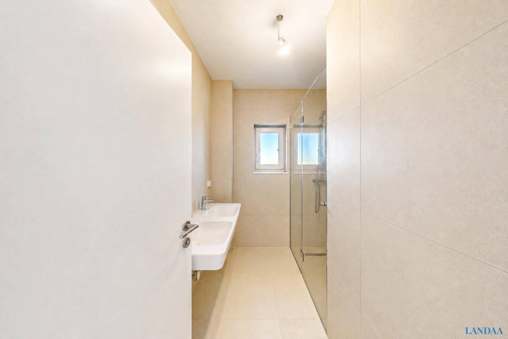 Modernes Badezimmer mit großem Waschbecken, begehbarer Dusche und Fenster.
