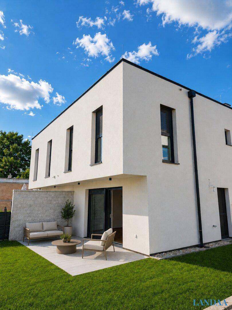 Moderne Rückansicht des Hauses mit möblierter Terrasse und gepflegtem Garten.