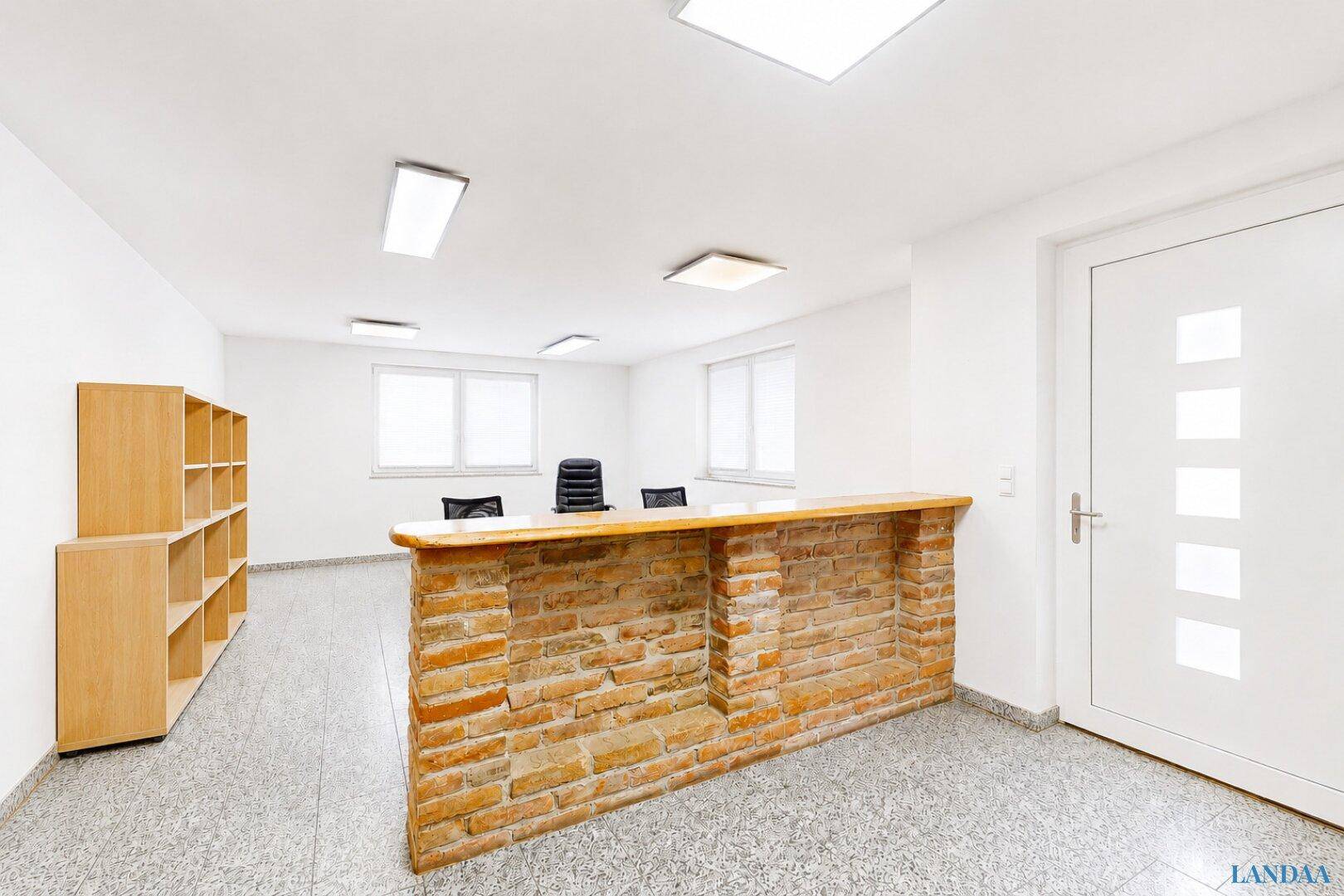 Heller Büroraum mit einer Ziegelstein-Rezeption, hellem Terrazzoboden und großen Fenstern für Tageslicht.