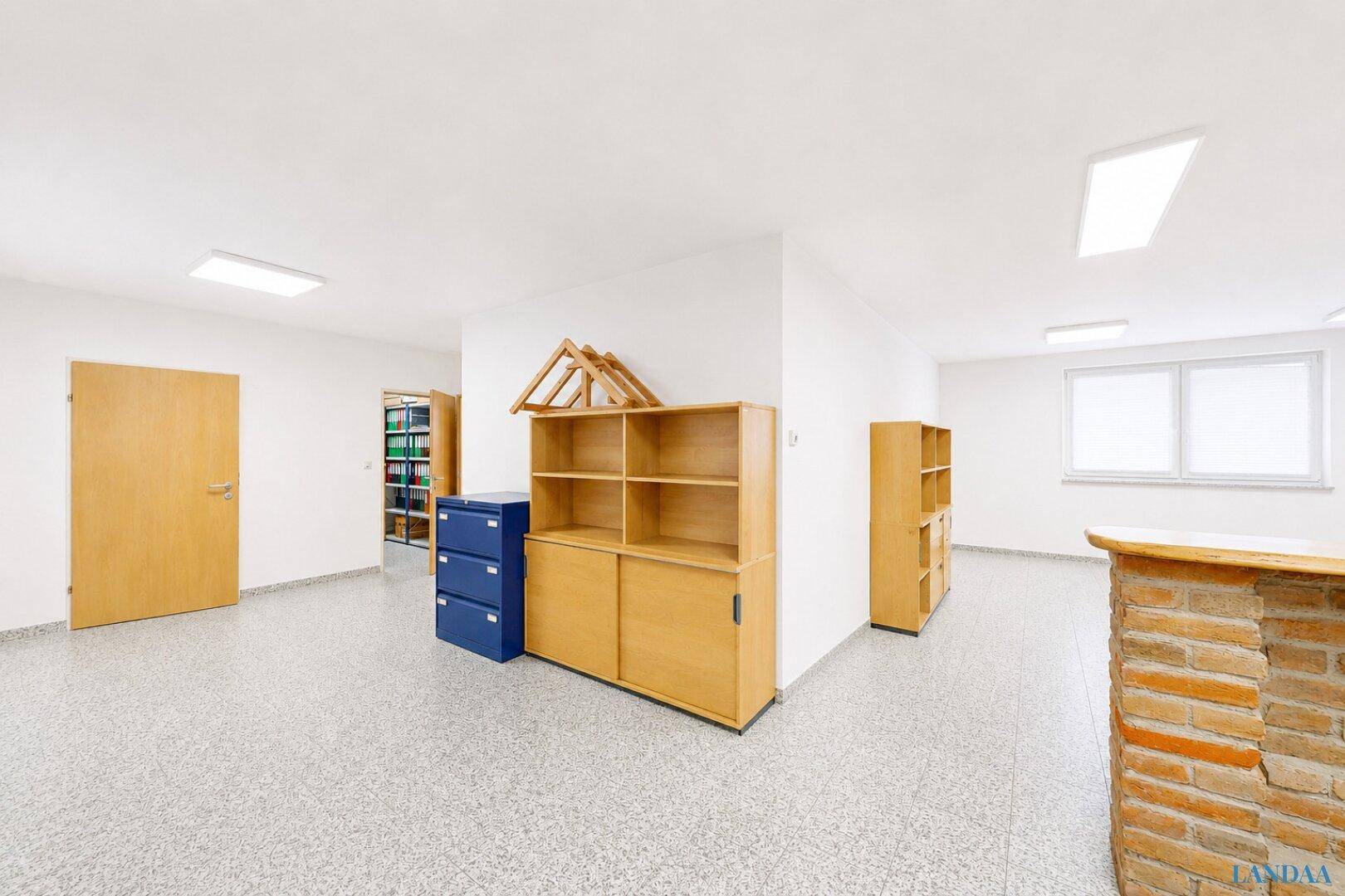 Heller Büroraum mit hellen Holzschränken, Terrazzoboden und weißen Wänden, ideal für Arbeitsbereiche.