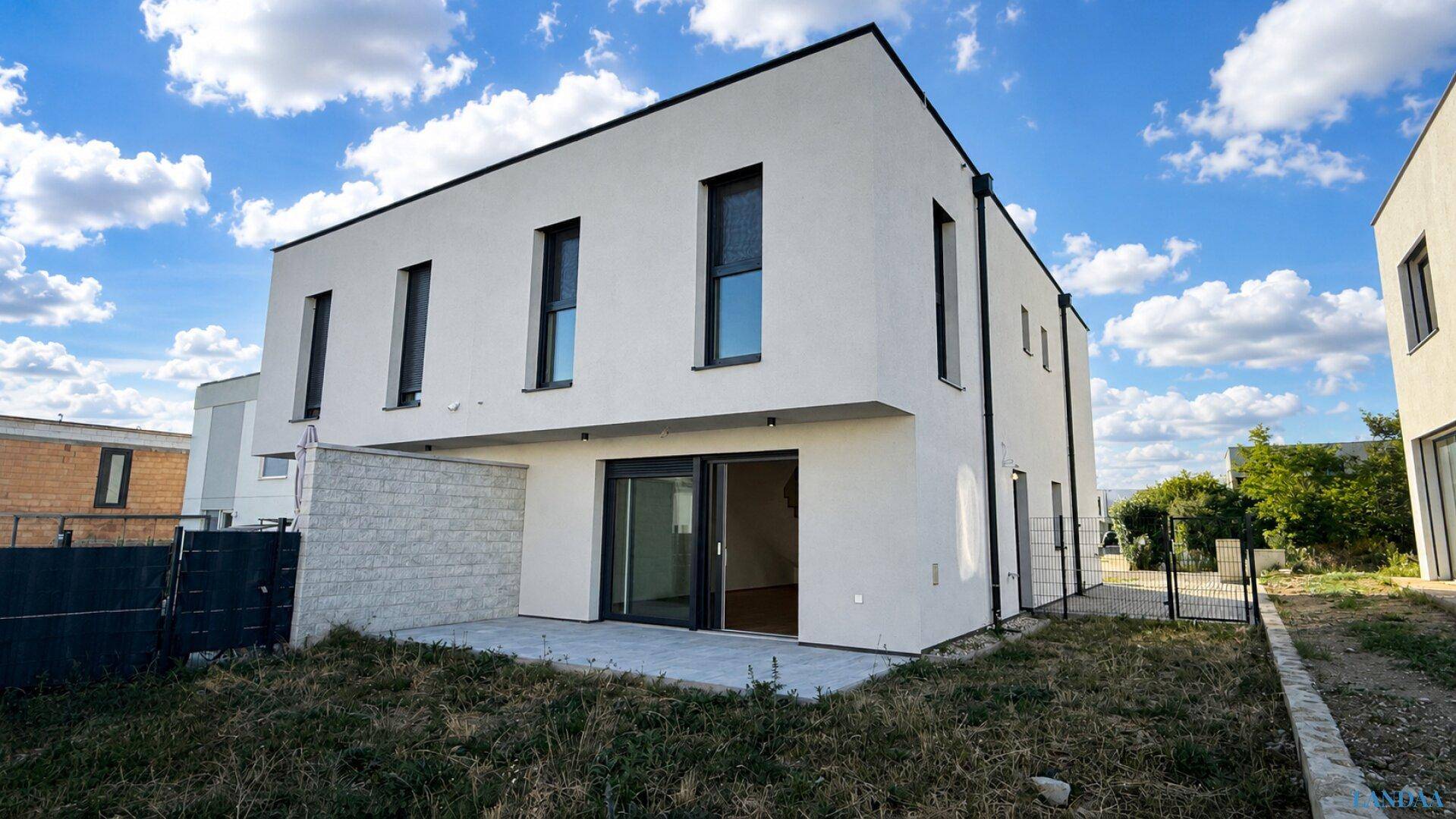 Rückansicht des modernen Hauses mit Terrasse und großem, noch ungestaltetem Garten.