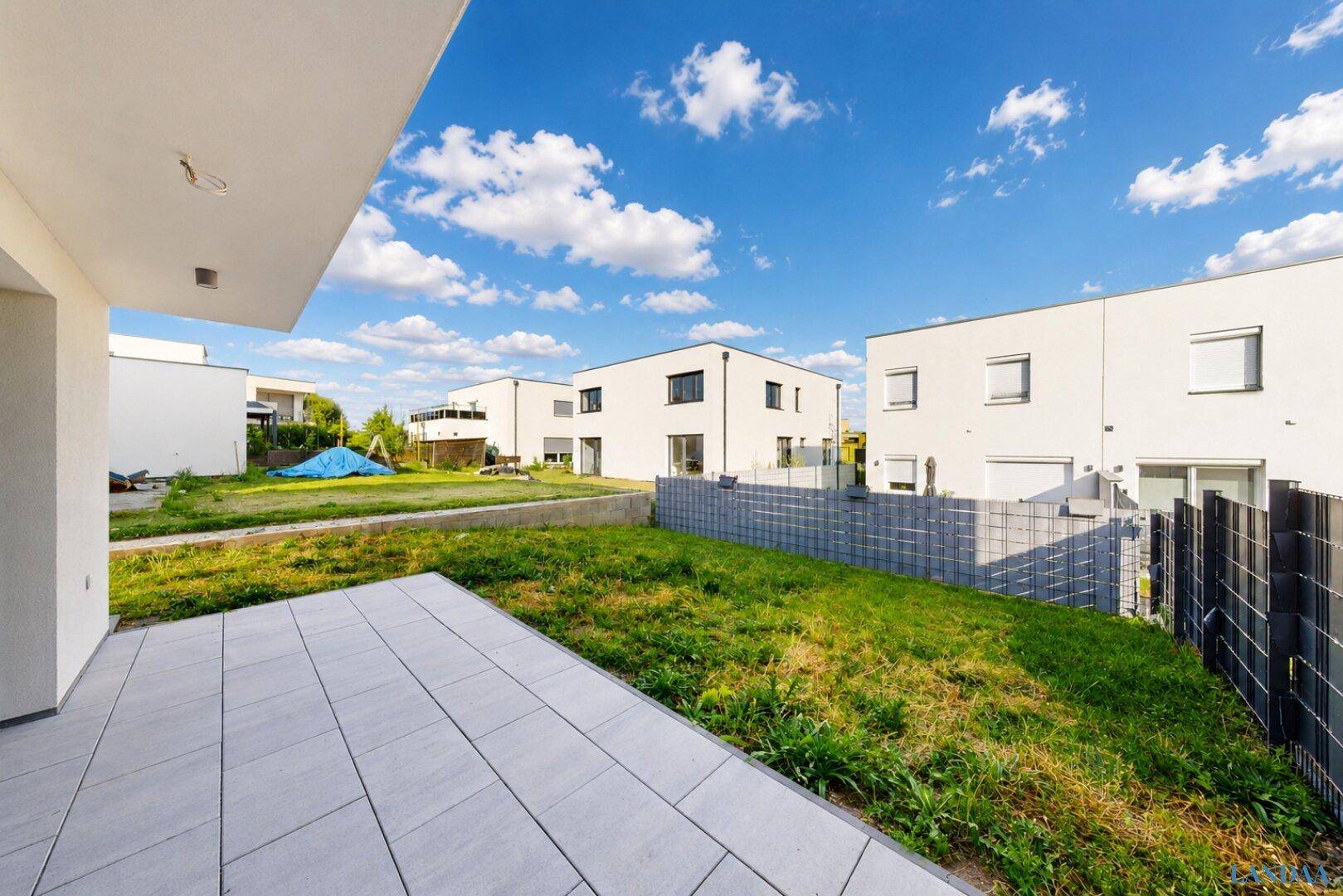 Terrasse mit Blick auf den Garten und die umliegenden modernen Häuser der Siedlung.