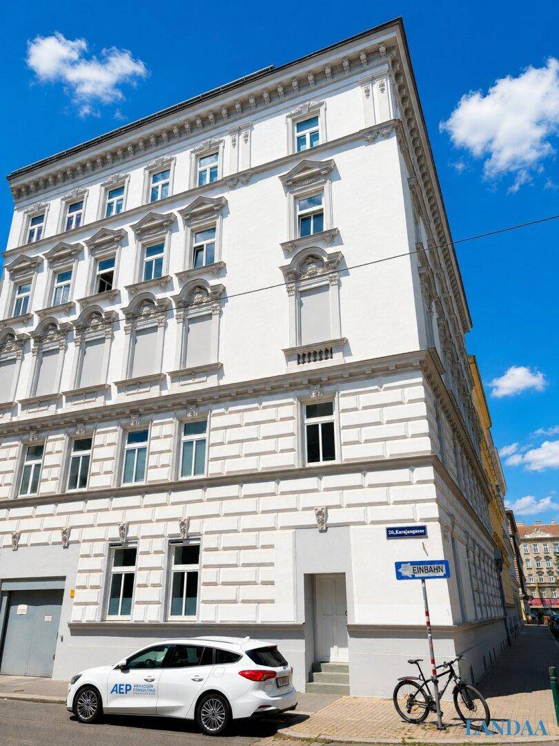 Historisches Gebäude mit weißer, reich verzierter Fassade unter blauem Himmel.
