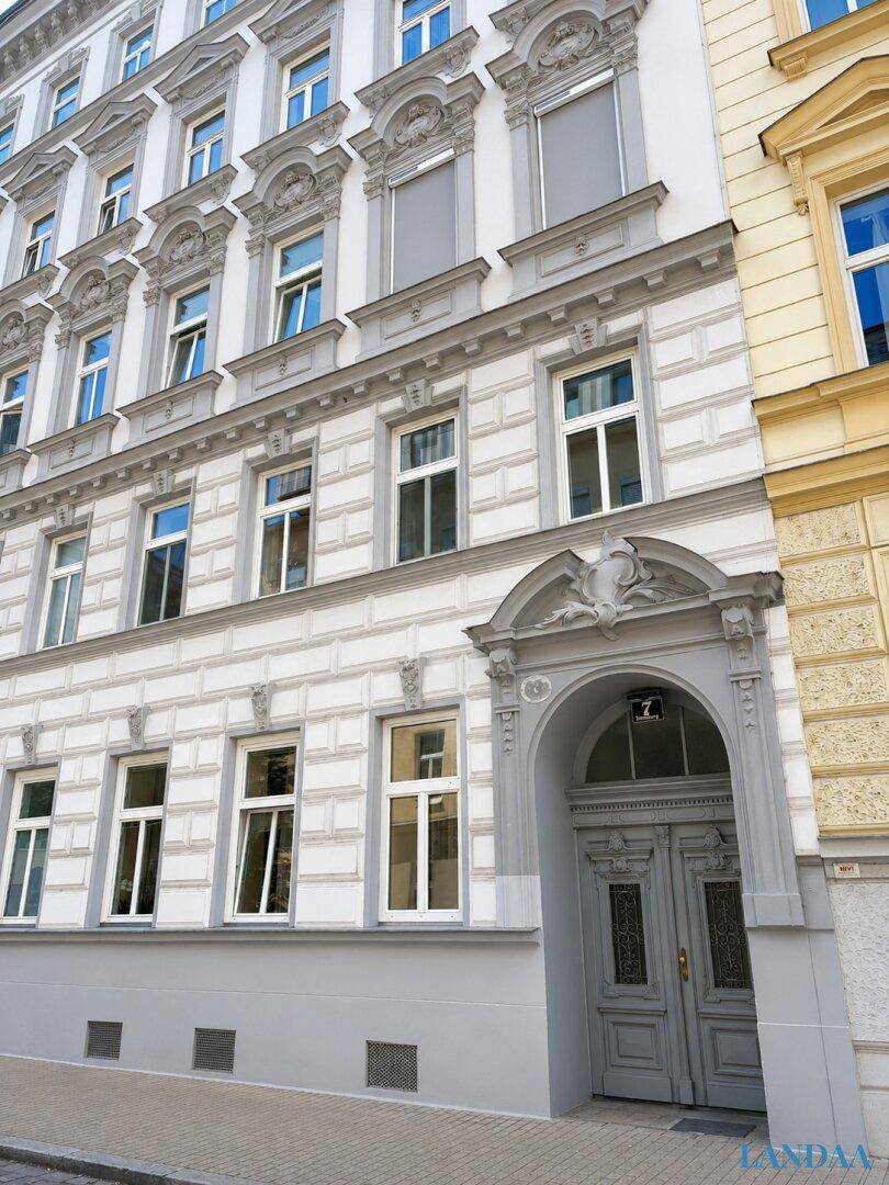 Detailansicht des Haupteingangs mit einer verzierten grauen Doppeltür und klassischer Fassade.