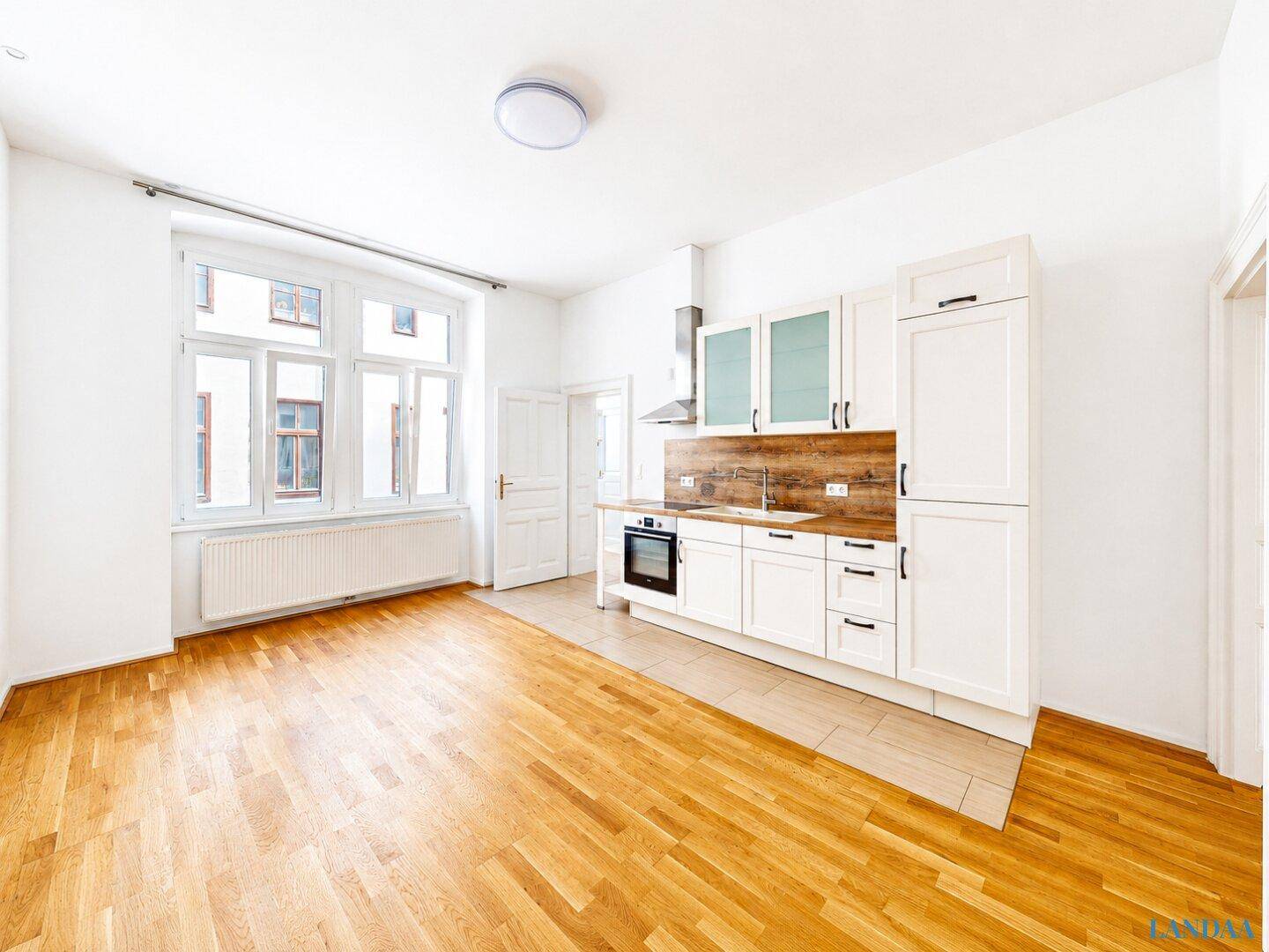 Moderne Einbauküche mit weißen Fronten und Holzakzenten, kombiniert mit einem hellen Wohnbereich.