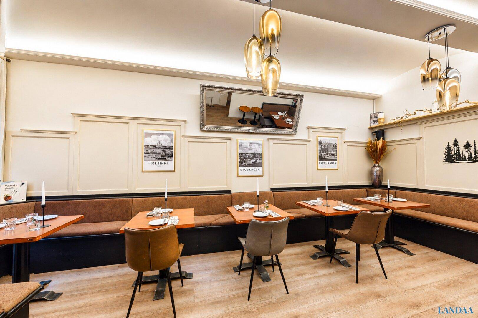 Heller Restaurantraum mit beigen Wänden, braunen Sitzbänken und modernen Hängelampen über den Tischen.