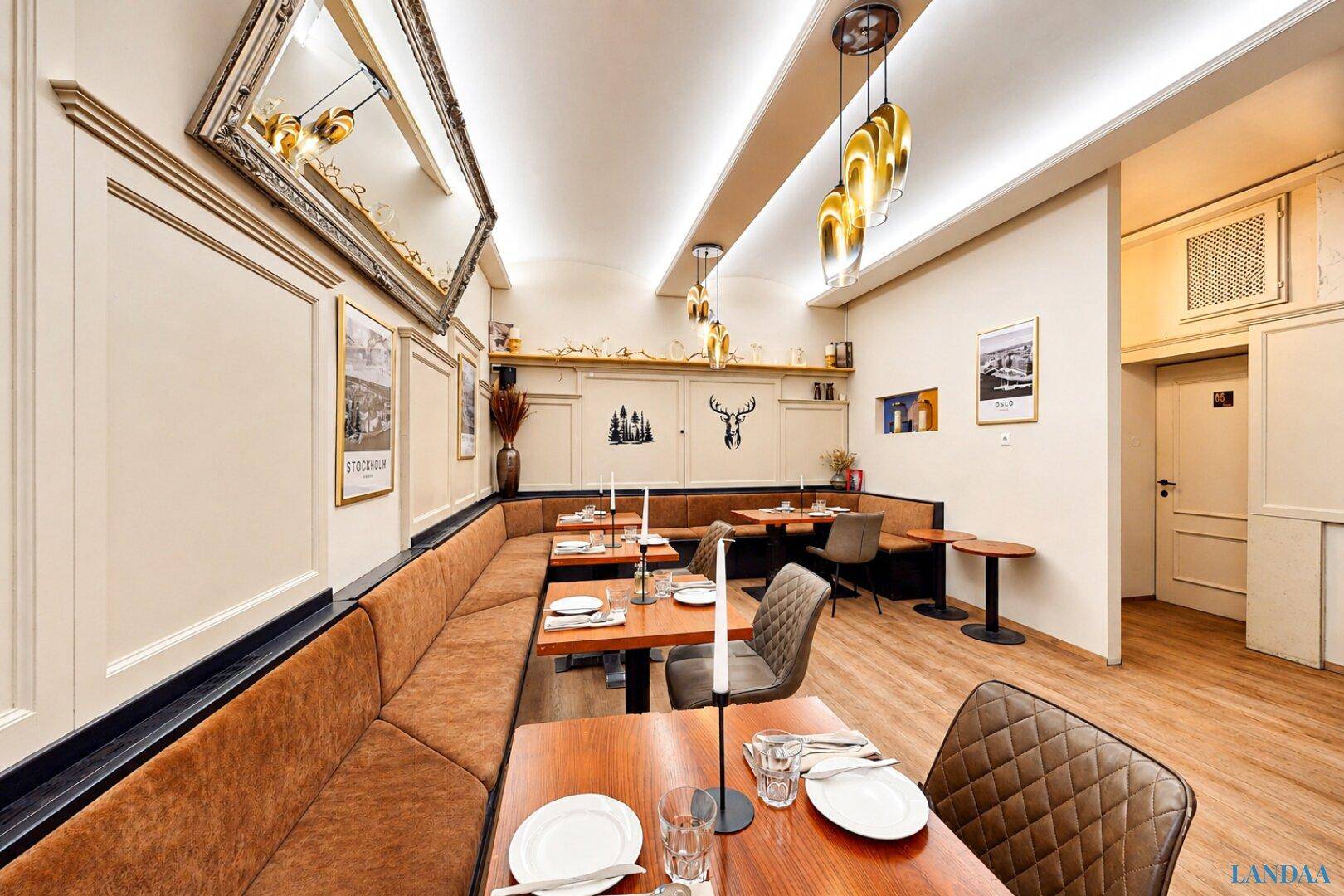Langer Restaurantbereich mit durchgehender Sitzbank, Holztischen und einem großen Spiegel an der Wand.