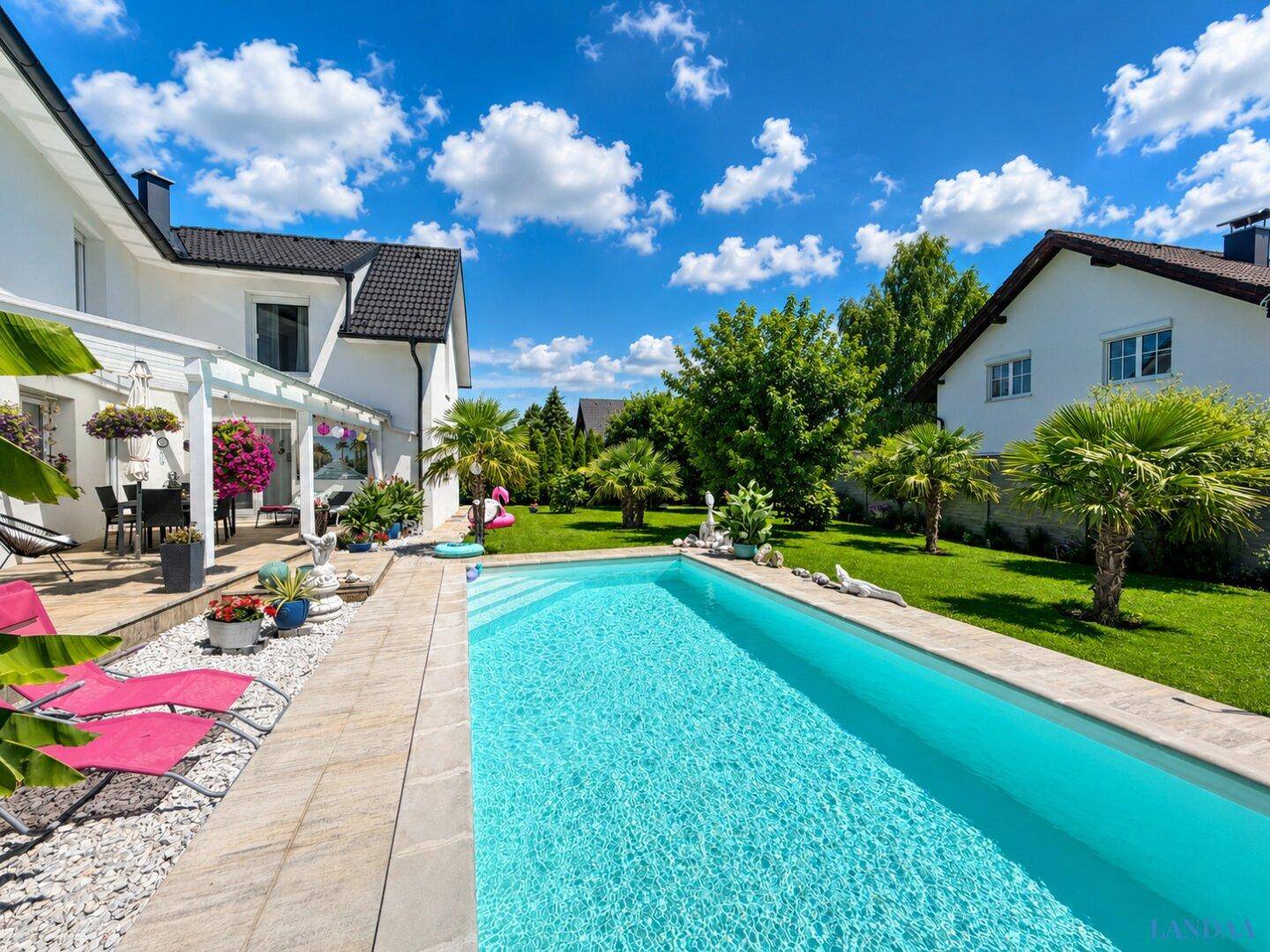 Gepflegter Außenbereich mit erfrischendem Pool, Liegestühlen und üppiger Bepflanzung.