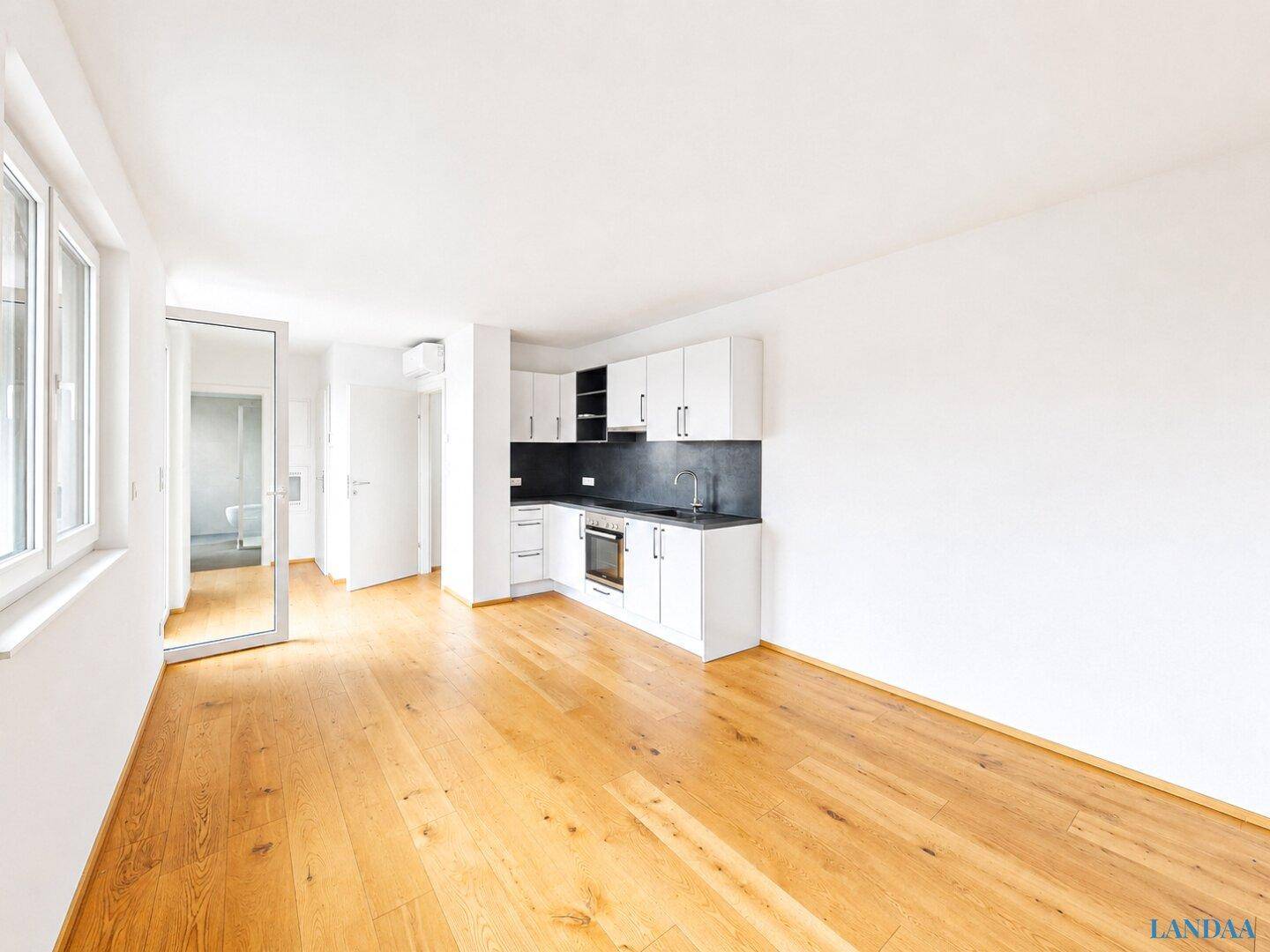 Geräumiger, heller Wohn-Essbereich mit Holzboden und großen Fenstern.