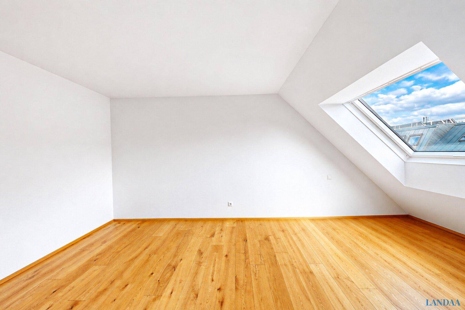 Geräumiges Schlafzimmer im Dachgeschoss mit Holzboden und Dachfenster.