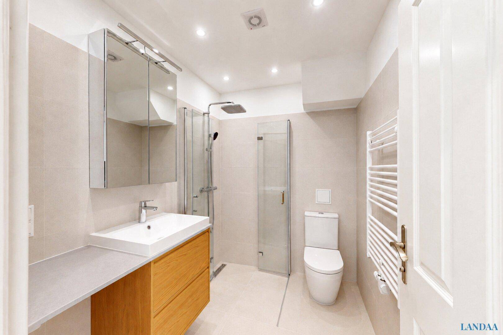 Modernes Badezimmer mit begehbarer Dusche, Einzelwaschbecken und beheiztem Handtuchhalter.