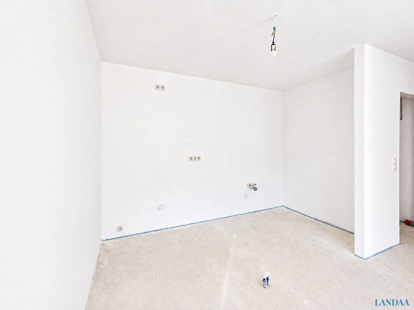 Unmöblierter Raum mit Anschlüssen für eine Küche, bereit für den Einbau.