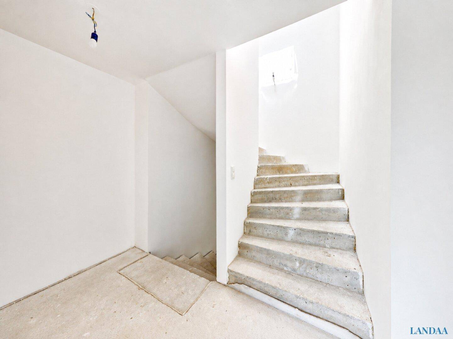Unfertiges Treppenhaus mit Betontreppe, das in die oberen Stockwerke führt.