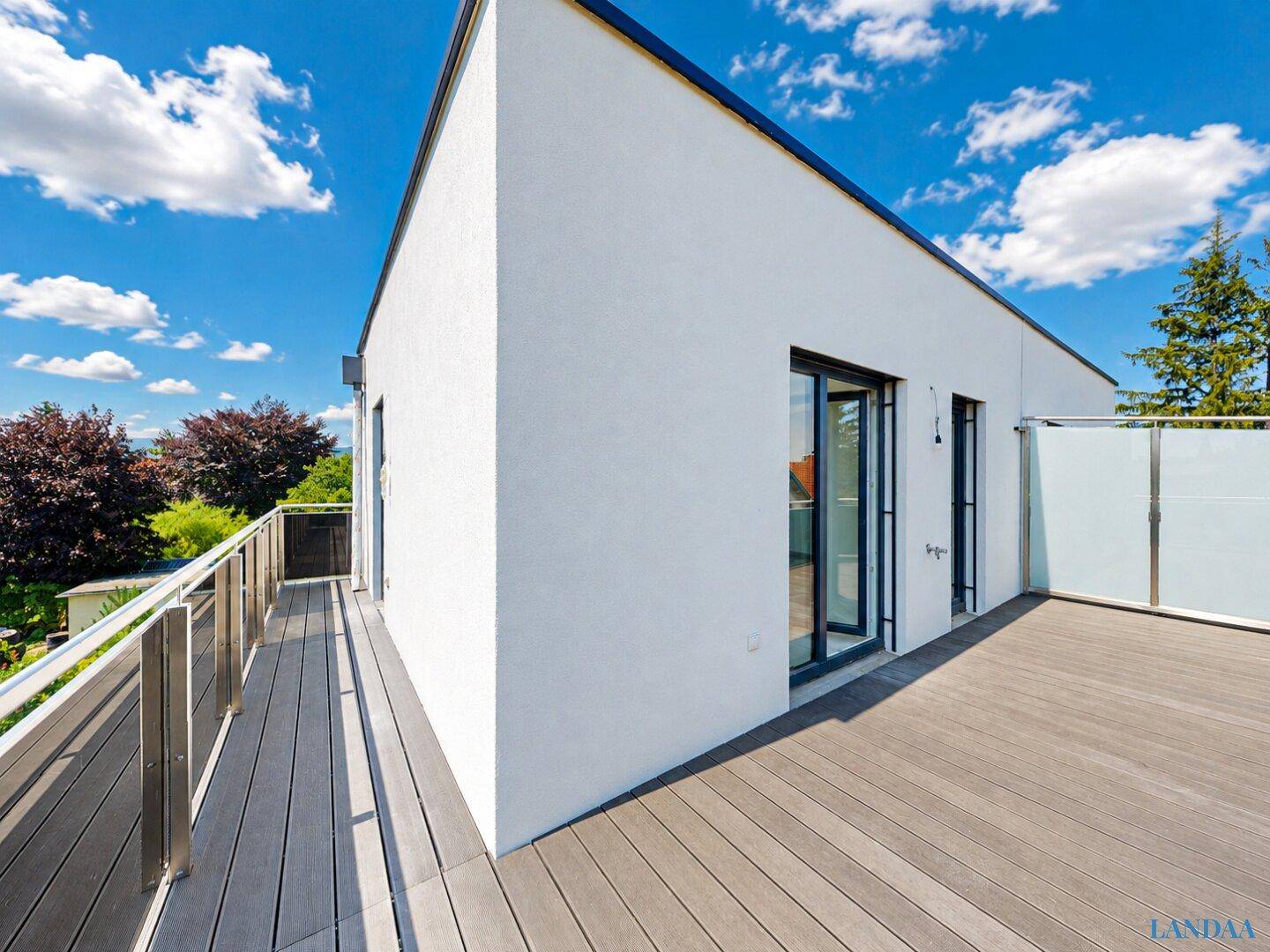 Große Dachterrasse mit Holzboden und Glasgeländer, bietet viel Platz im Freien.