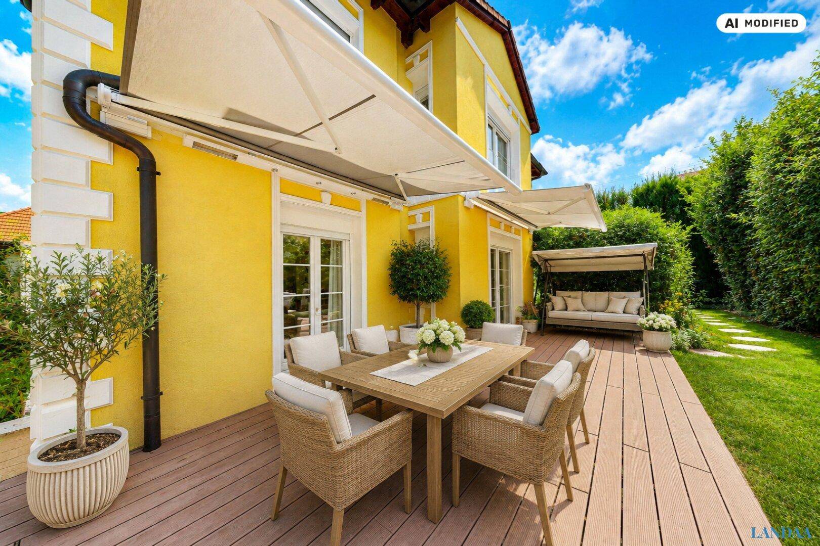 Große Holzterrasse mit Esstisch, Lounge-Bereich und Markise, umgeben von Grün.