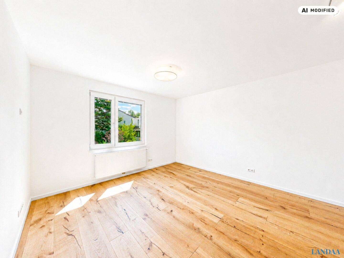Unmöbliertes Zimmer mit Holzboden, großen Fenstern und viel Tageslicht mit grüner Aussicht.