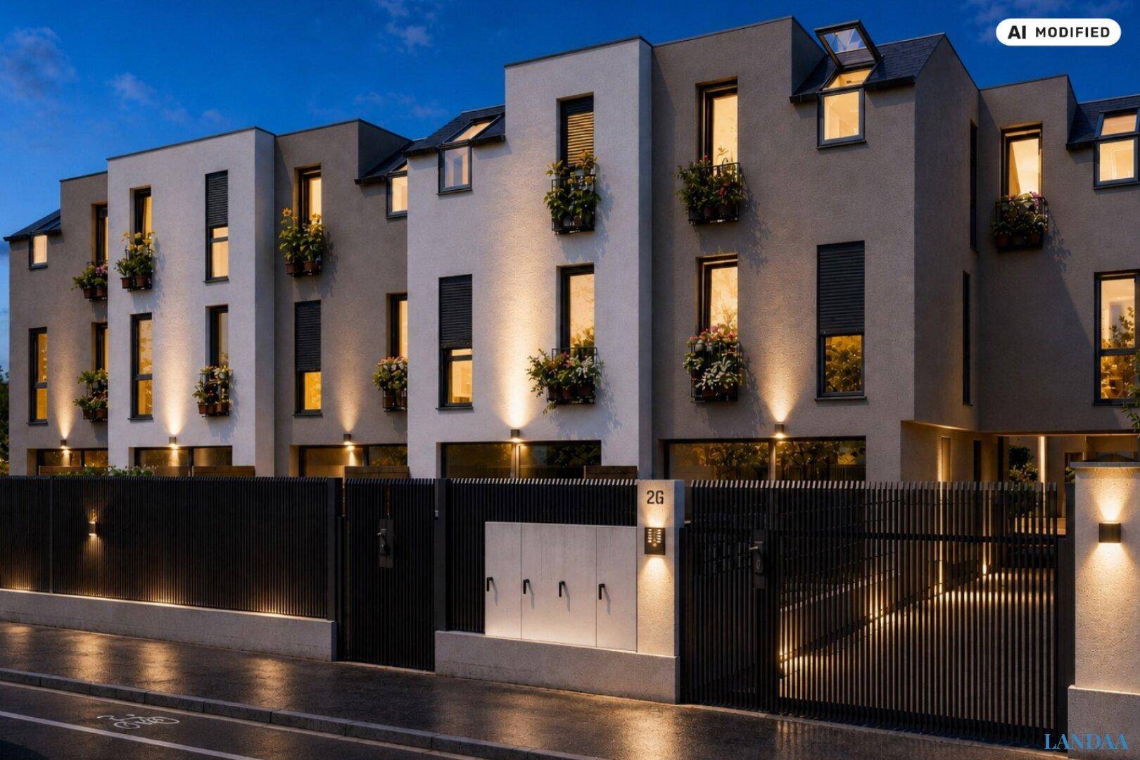 Moderne Reihenhäuser mit beleuchteter Fassade und Eingangsbereich am Abend.