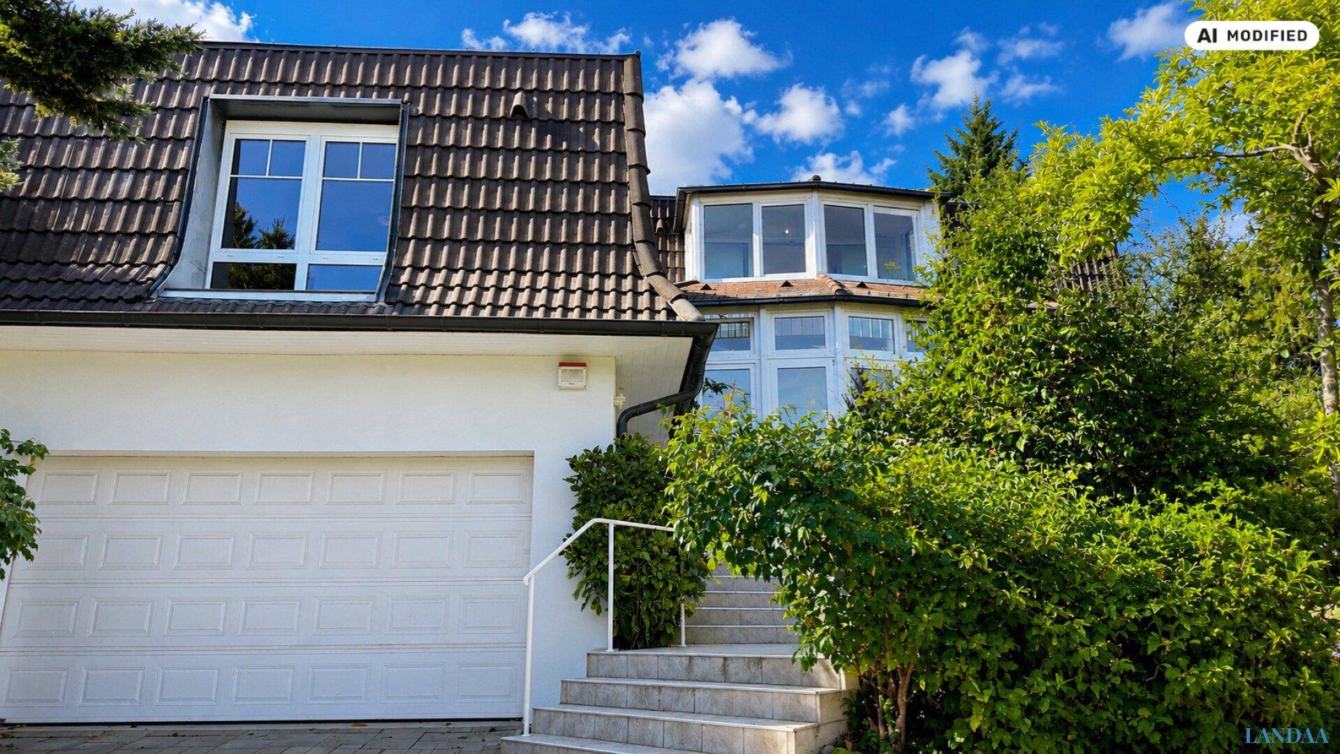 Vorderansicht des Hauses mit Garage, Mansarddach und Treppenzugang zum Eingangsbereich.