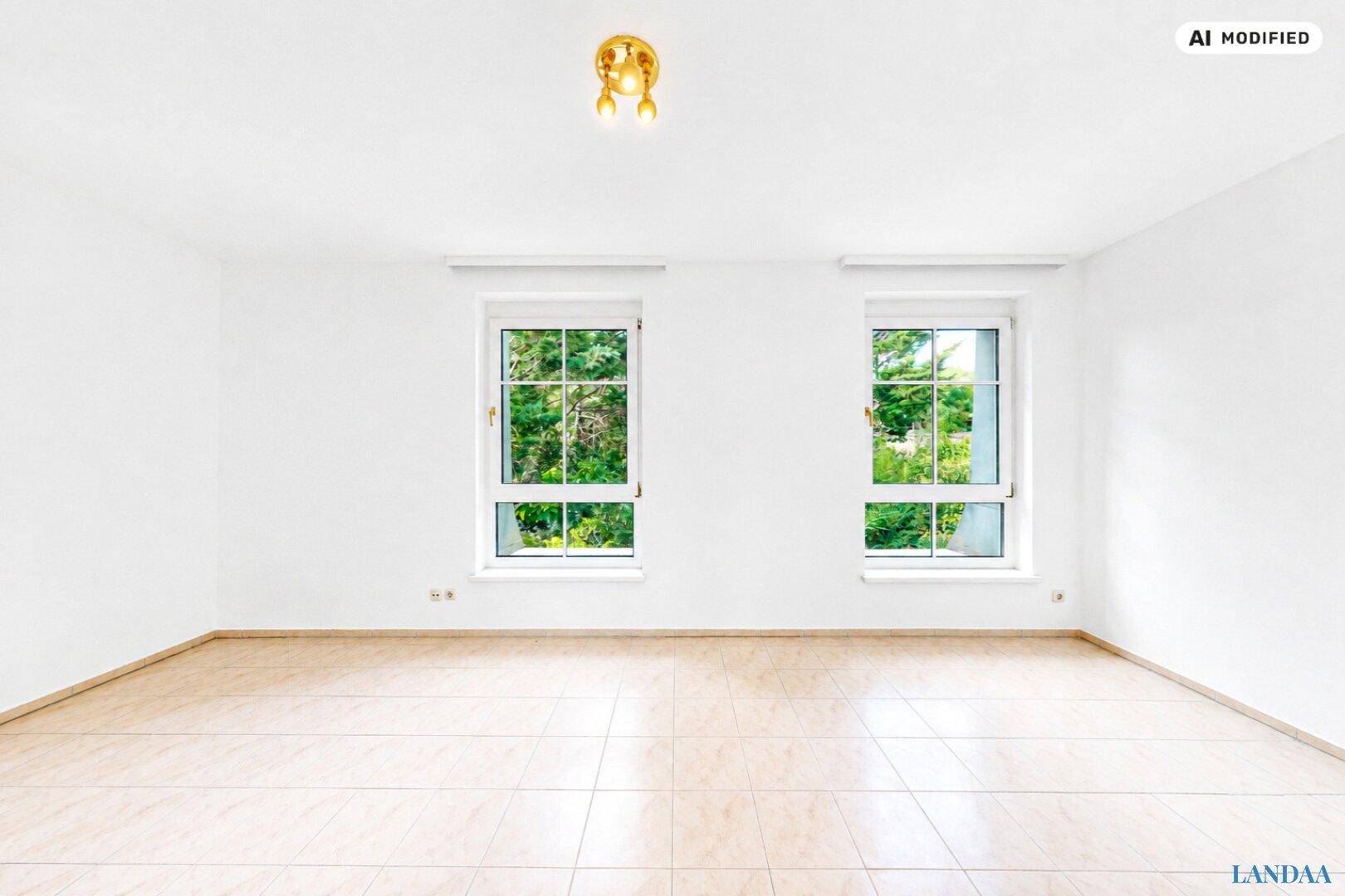 Leerer Raum mit hellen Wänden, Fliesenboden und zwei großen Fenstern mit Blick ins Grüne.