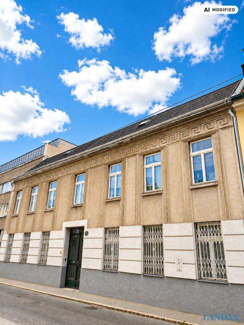 Historisches Gebäude mit einer strukturierten Fassade, großen Fenstern und dekorativen Elementen unter blauem Himmel.