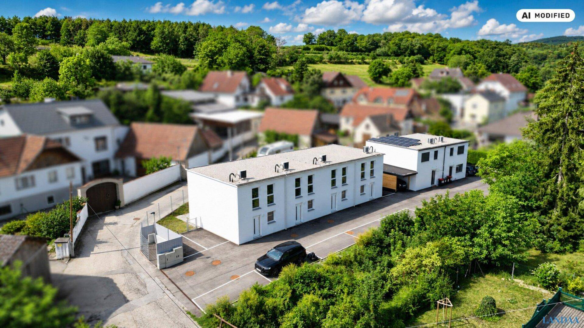 Luftaufnahme einer Wohnsiedlung mit mehreren Gebäuden und viel Grün in der Umgebung.