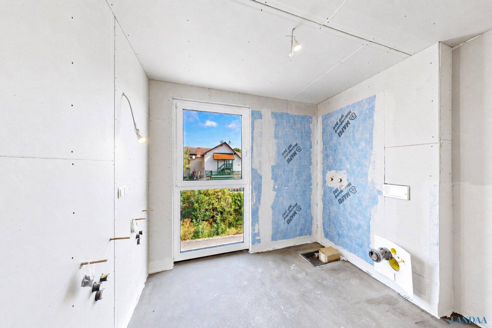 Rohbau-Badezimmer mit vorbereiteten Anschlüssen, Fenster und Abdichtung für zukünftige Installationen.