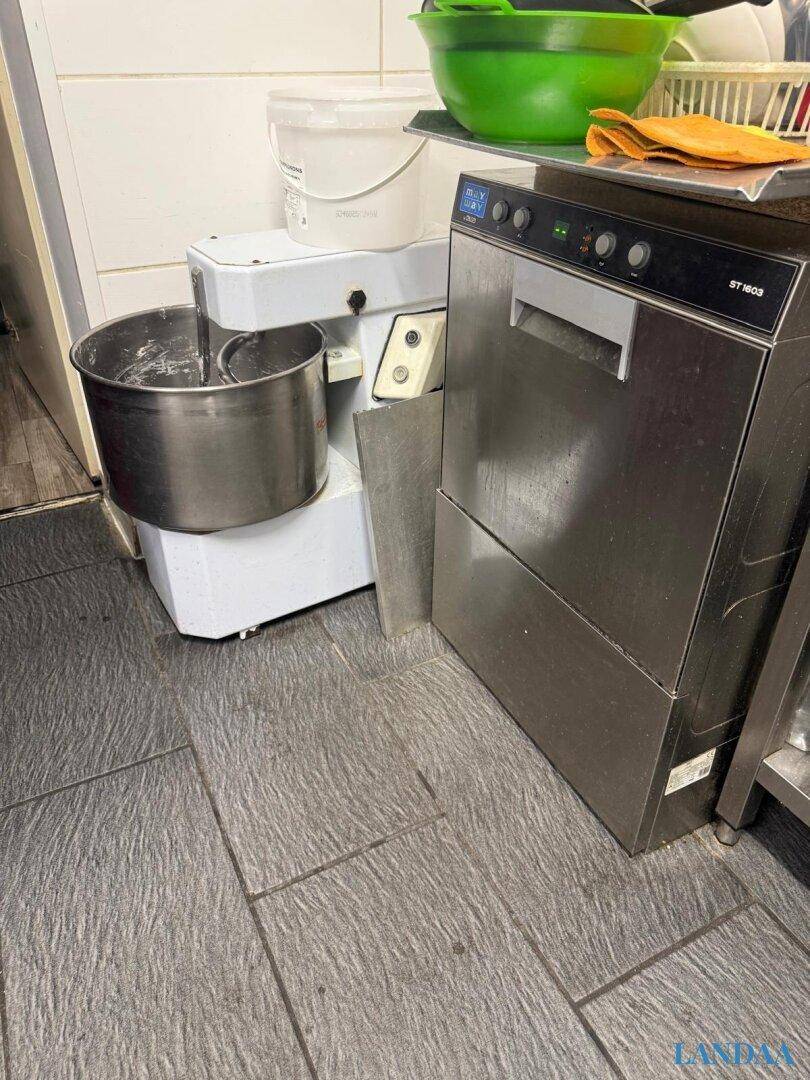 Professionelle Küchengeräte wie eine große Teigmaschine und ein gewerblicher Geschirrspüler für den Betrieb.
