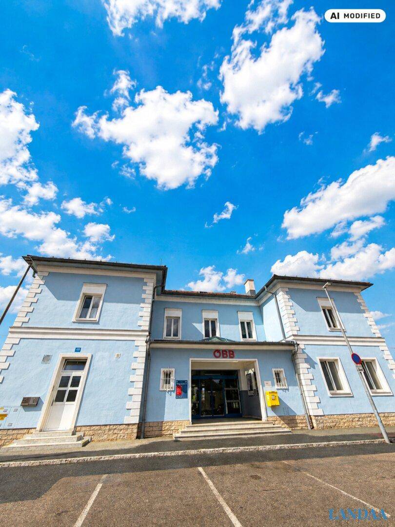 Historisches Gebäude mit hellblauer Fassade und weißem Stuck, möglicherweise ein ehemaliger Bahnhof.