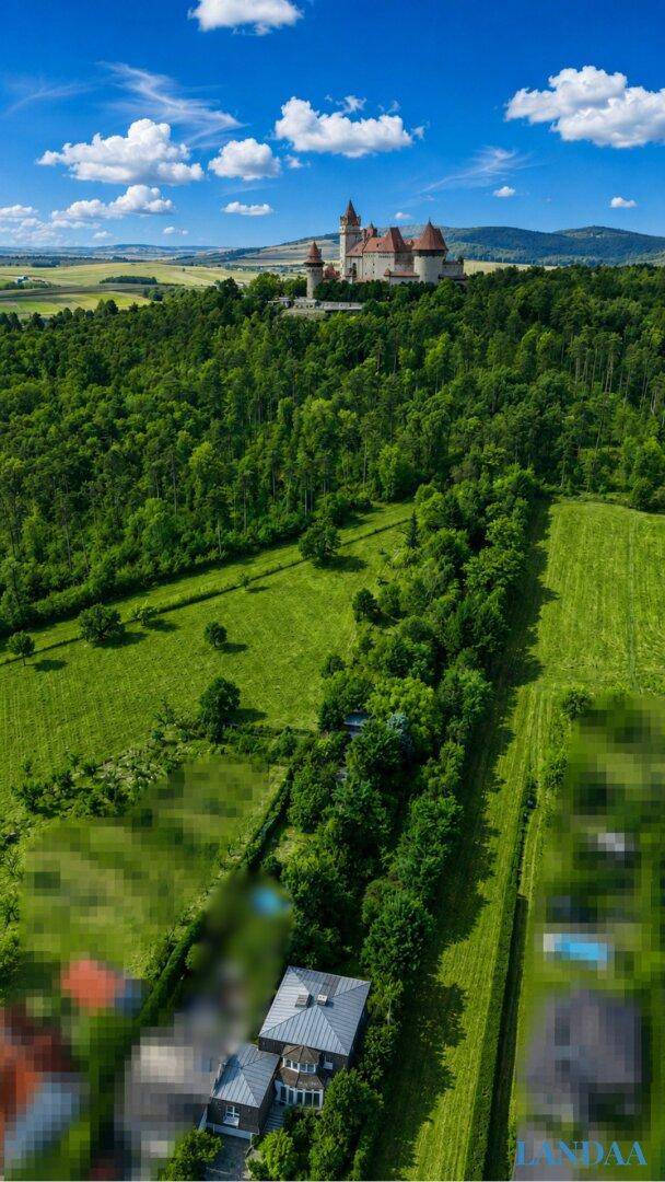 Vertikale Luftaufnahme des Hauses in ländlicher Umgebung mit Feldern, Wäldern und einer Burg.